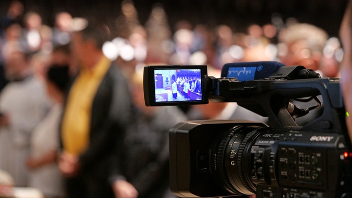 Eine Kamera filmt eine Menschenmenge.