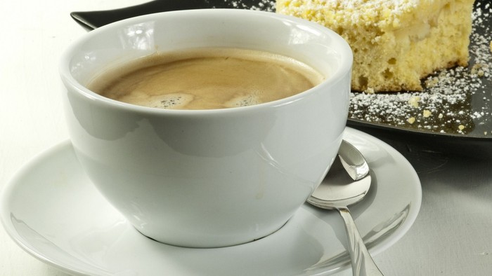 Eine Tasse Kaffee und ein Stück Kuchen auf einem Teller