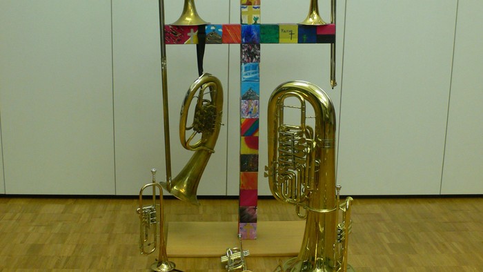 Viele Blechblasinstrumente stehen vor einer weißen Wand