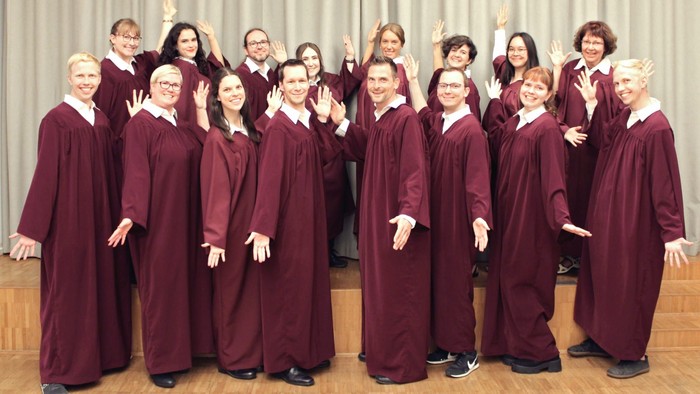 Ein Chor steht in roten Roben auf einer Bühne