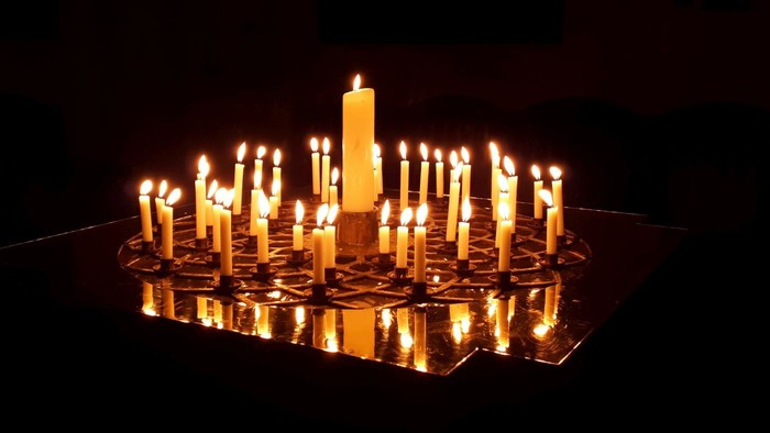 Ein beleuchtetes Schachbrett mit vielen brennenden Kerzen, eine Kerze ist größer als die anderen