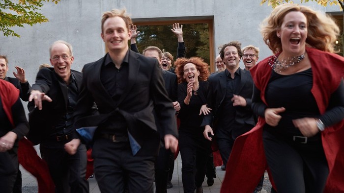 Eine Gruppe von Menschen in formeller Kleidung rennt fröhlich.
