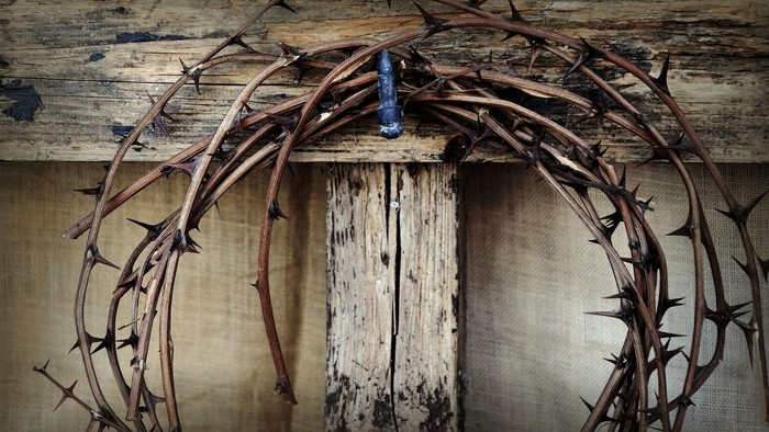 En rustik tornekrans hænger over en gammel trædør med en blå flaske i midten.