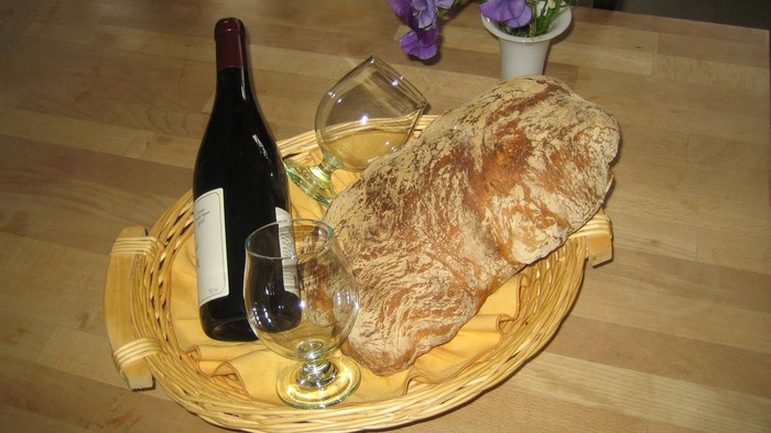 En flaske vin, to glas og en brødstang på en vickeret trays på bordet