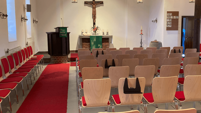 Die Kirche hat Holzstühle und rote Teppiche.
