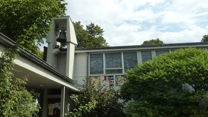 Haus mit grünem Gebüsch und Bäumen im Vordergrund