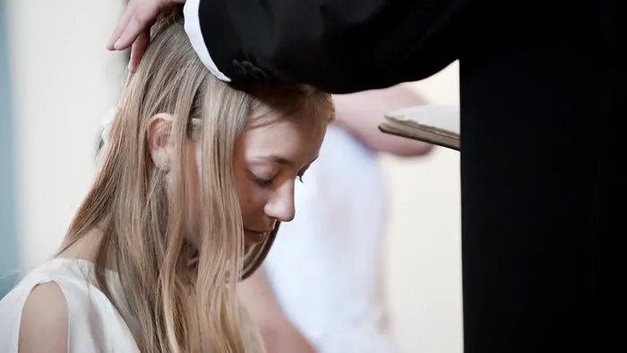 Præsten lægger sin hånd på konfirmandens hoved