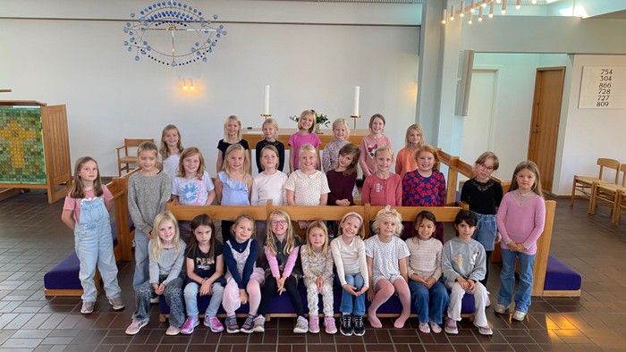 En gruppe børn og voksne poserer til et billede i en kirke