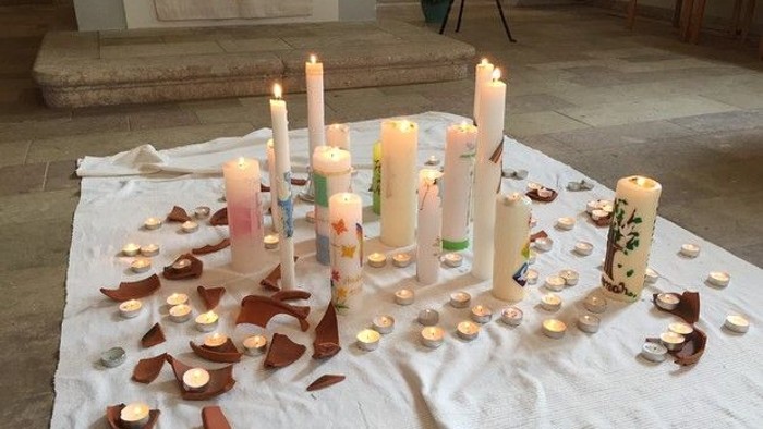 Ein Tisch mit vielen Kerzen und Teelichtern, bedeckt mit einer weißen Decke