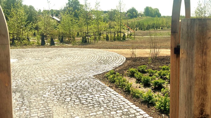 En stenlagt vej gennem en park med træer og buske