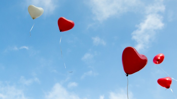 Herzförmige Ballons schweben im blauen Himmel