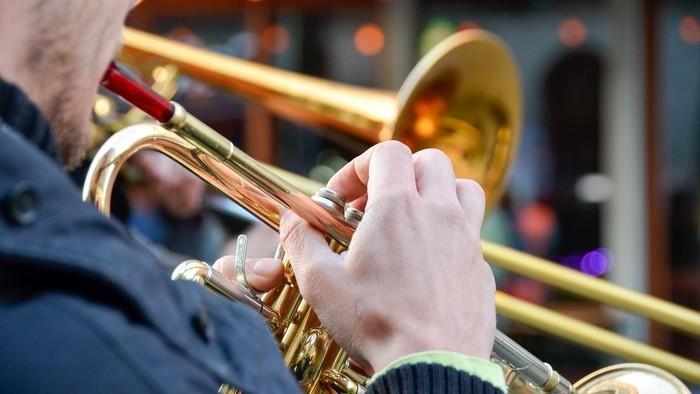 Eine Person, die Trompete spielt, mit Fokus auf Hände und Instrument.