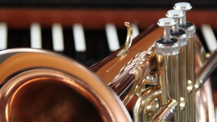 Ein goldenes Musikinstrument liegt vor einem Klavier.