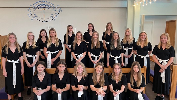 En gruppe kvinder i svart og hvidt tøj samlet i kirke.