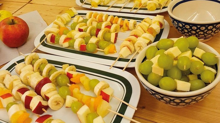 Bunte Obstspieße und frische Trauben, arrangiert auf Tabletts und in einer Schüssel für eine gesunde Snack-Auswahl.