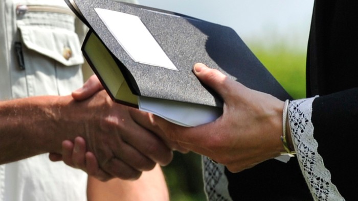 En person overreder en mørk bog til en anden person.