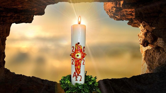 Eine brennende Kerze mit den Symbolen „2020“ und „2021“ steht in einer Höhlenöffnung vor einem ruhigen Sonnenuntergangshintergrund.