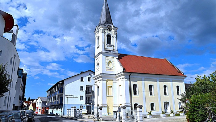 Kirchengemeinde mit weißem Turm und rotem Dach in kleiner Stadt