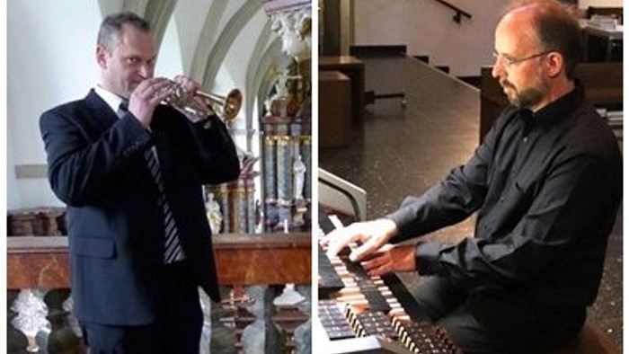 Ein Mann spielt in einem Raum eine Trompete, ein anderer sitzt an einem Keyboard.