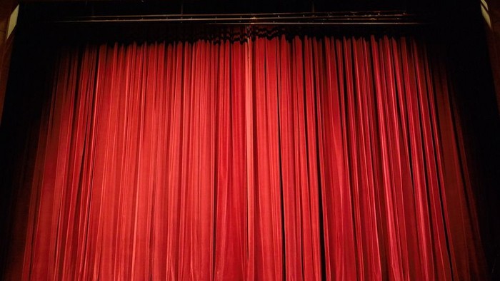 Rote Vorhänge, die eine Bühne bedecken.