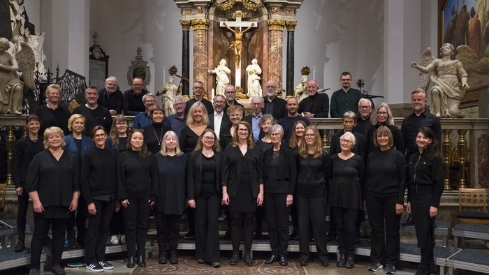 Et korhold poser formelt inde i en prægtig kirke med udsmykkede dekorationer og statuer.