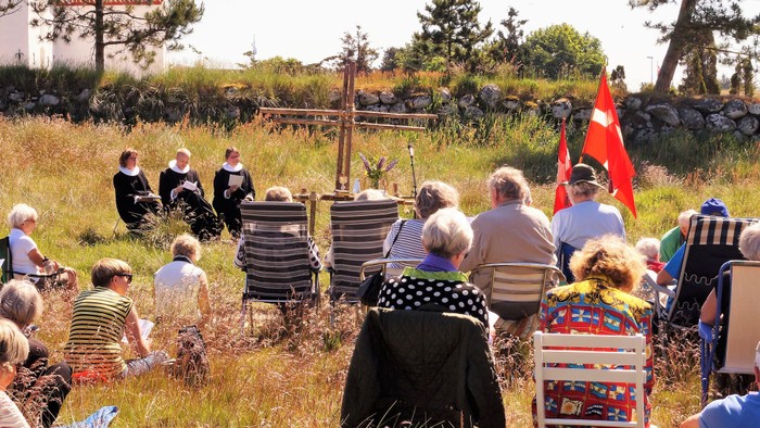 En gruppe af mennesker sidder på en eng med barnevogne og flag.