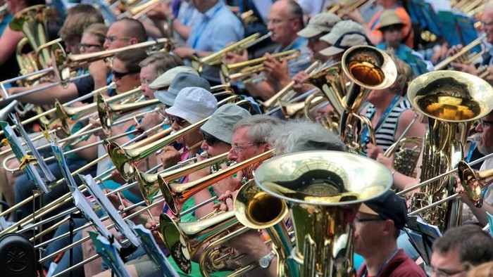 Eine lebhafte Blaskapelle, die auf einem belebten Open-Air-Event vor begeistertem Publikum musiziert.