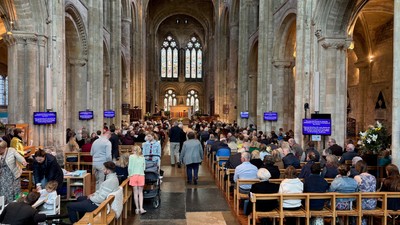 A crowded cathedral interior with attendees seated in pews during a service or gathering.