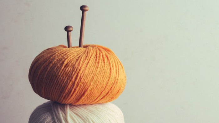 En gulerodformet garnhop med to strå, stillet på en hvid garnhop