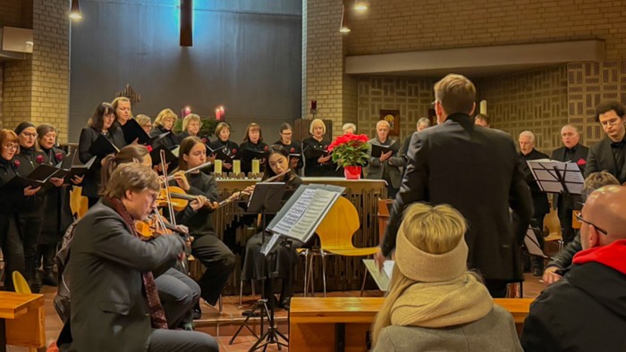 Eine Kirchenchor probt in einem Gotteshaus mit Kreuz und Musikern