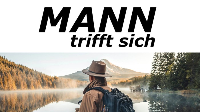 Ein Mann mit Rucksack sitzt am See und schaut auf den Berg