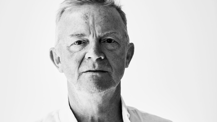 Sort-hvidt portræt af Mich Vraa iført en lys, løstsiddende skjorte.