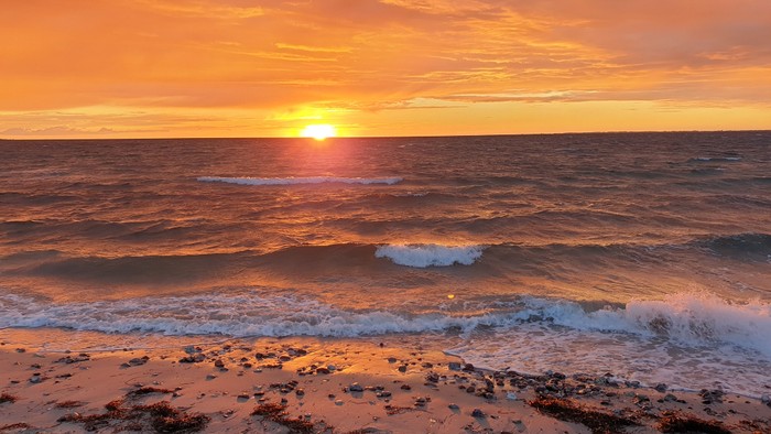 Ein wunderschöner Sonnenuntergang am Meer mit sanften Wellen und orangefarbenem Himmel