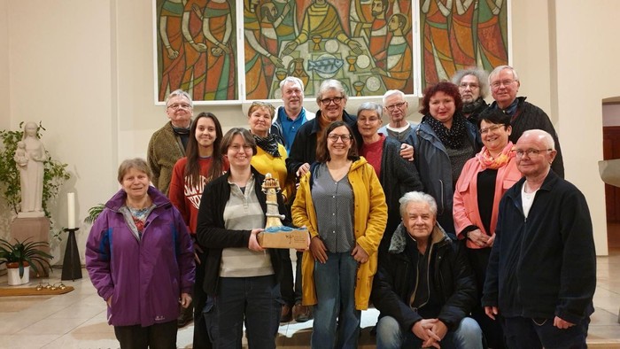 Eine Gruppe von Menschen posiert vor einem Kirchenfenster