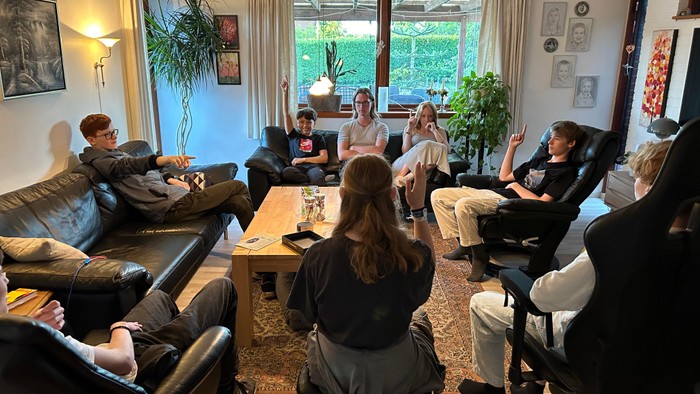 En gruppe af venner sidder i et stue og snakker.