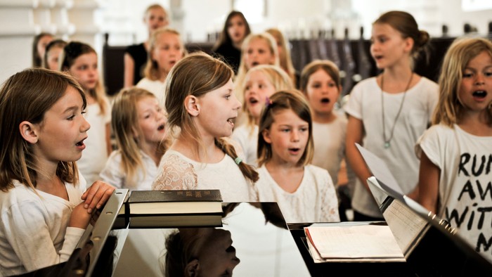 En gruppe børn synger i kor i en kirke.