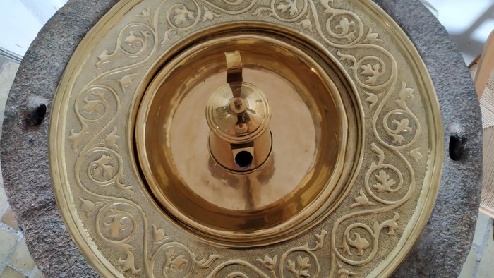 Guldfarvet metalbeslag med indviklede mønstre på en stens overflade