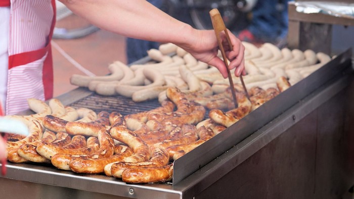 Pølser, der bliver grillet og vendt, på en grill