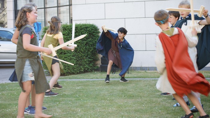 Børn spiller med stokkevåben på græsplænen