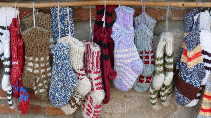 Forskellige strikkede sokker hængende på en træstang