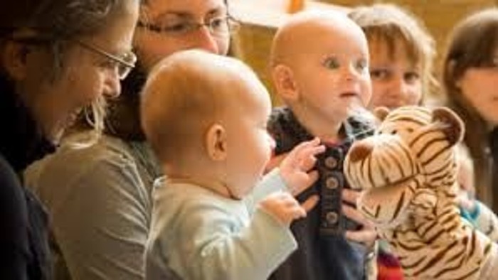 En gruppe børn og voksne, hvor børnene holder legetøj og ser opad.