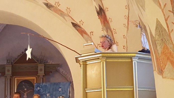 En præst preker fra en pulpet i en smukt, udsmykket kirke.