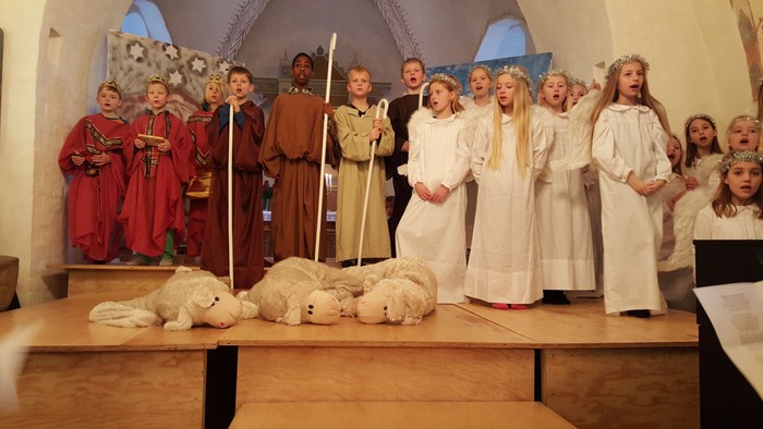 En gruppe børn i kostumer opfører et skuespil i en kirke.