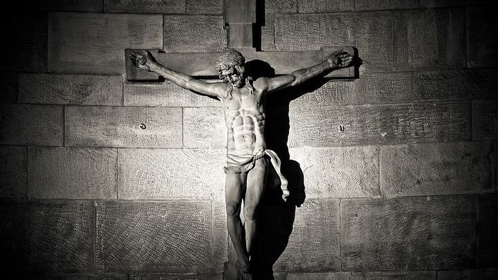 Eine Statue von Jesus Christus am Kreuz vor einer Steinmauer.