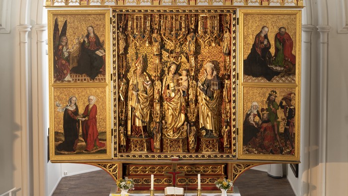 Geschnitzter Altar, in der Mitte Figuren, an den Seiten vier bemalte Tafeln mit biblischen Szenen