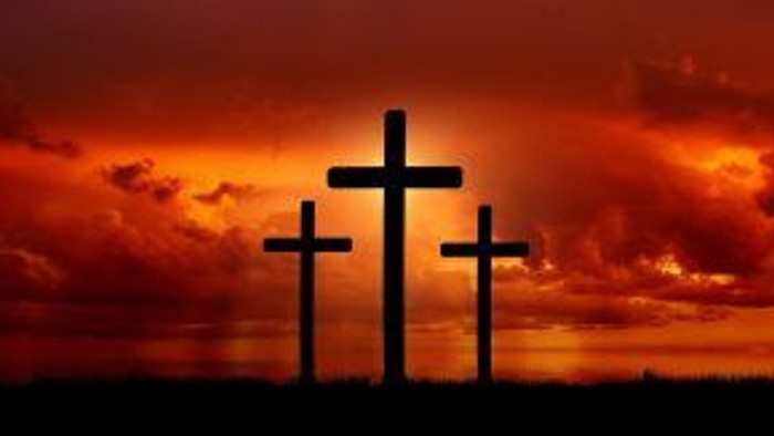 Tre kors med en rødgul nattehimmel bag.