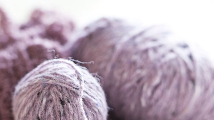 En stabel lilla garnbolle, der er delvist udeklædt.