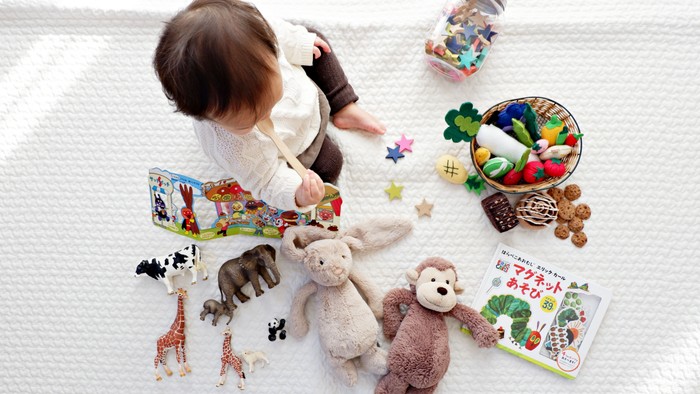 A child playing with toys and books on a rug