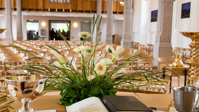 En festligt stillet bord med blomsterarrangement og åben bog