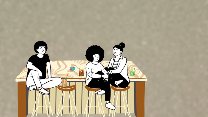 Drei Personen sitzen an einem Tisch und trinken Getränke